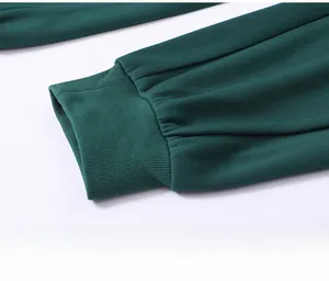 Detail of dark green ribbed knit sweatpants featuring elastic ribbed ankle cuffs design
