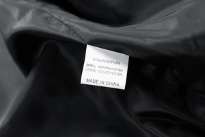 Close-up of internal composition tag on black fleece jacket showing 100% polyester fabric