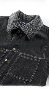 Détail d'une veste en jean noire avec col en polaire grise et poche à bouton métallique