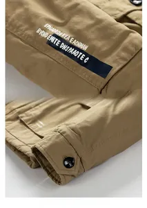 Detail of khaki workwear jacket showing decorative patch and buttoned cuff design