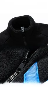 Detail of black polar fleece jacket showing textured fabric and blue geometric embroidery