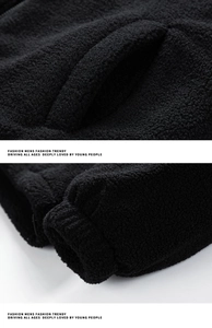 Detail view of black sherpa jacket showing pocket stitching and elastic ribbed cuffs