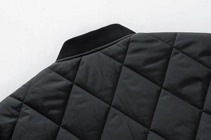 Detailansicht der schwarzen Rautensteppung und des gerippten Stehkragens der Jacke