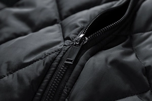 Details einer rautenförmig gesteppten Jacke mit Metallreißverschluss und mattem Stoff