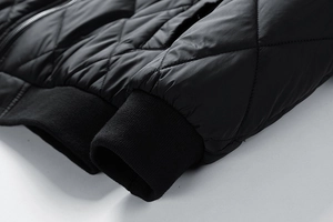 Detail der schwarzen Steppjacke mit Rautensteppung und elastischen Rippbündchen