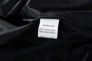 Detailansicht des inneren Pflegeetiketts einer schwarzen Polyester-Herrenjacke