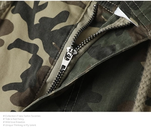 Dettaglio macro della cerniera in metallo e coulisse beige sui pantaloni mimetici