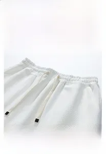 Detail view of white waffle fabric shorts with elastic drawstring waist and side pockets