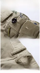 Détail macro du short cargo kaki montrant le bouton marron et les coutures renforcées