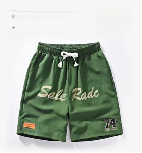 Detail of green quick-dry shorts featuring white drawstrings and NASA-style printed logos