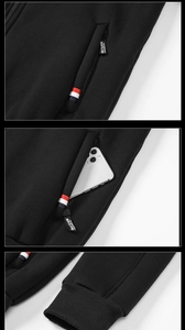 Detail of black fleece hoodie jacket with zippered pocket, brand tag, and ribbed cuffs