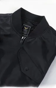 Detail of ribbed collar and snap button flap pocket on black MA1 flight jacket
