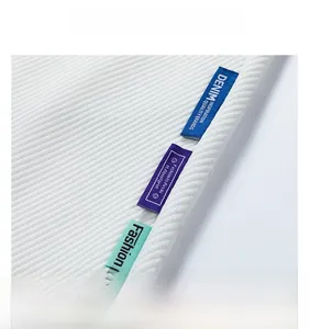 Dettaglio di pantaloni bianchi a costine con etichette colorate e doppie cuciture