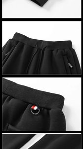 Detail of black fleece joggers showing elastic drawstring waist and tricolor tape pocket