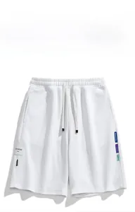 Dettaglio degli shorts bianchi in maglia a nido d'ape con coulisse e patch logo ricamato
