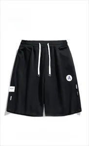 Détail du short en maille noire avec cordon de serrage et écusson brodé de style sportif