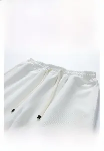 Détail du short blanc en maille gaufrée avec taille élastique à cordon et broderie lettre