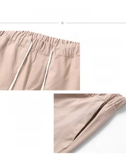 Detail of khaki cotton shorts featuring elastic waistband with white drawstrings and side pockets