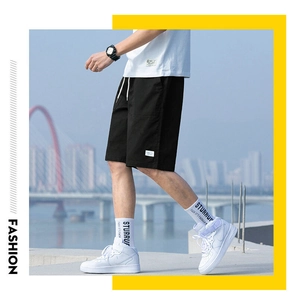 Detail of men's black cotton shorts with white woven patch and breathable texture