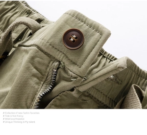 Detail of army green cargo shorts featuring elastic waist, drawstring, and metal zipper
