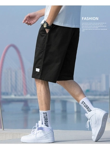 Close-up of black cotton cargo shorts featuring a minimalist white woven label on the leg