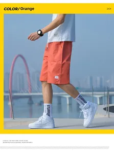 Street style shot of men's orange cotton shorts with drawstring and micro woven label