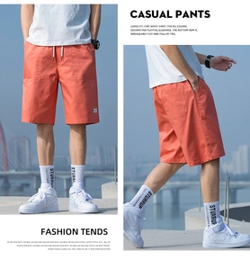 Detail of bright orange casual shorts with white drawstring and woven label
