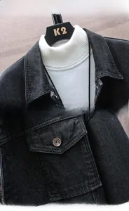 Detailed view of black denim jacket featuring a classic collar and embossed metal buttons