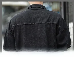 Detail of a black denim jacket showing the yoke stitching and twill fabric texture