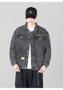 Close-up detail of dark grey washed denim jacket featuring metal buttons and chest pockets