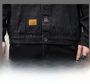 Close-up of deep black denim jacket featuring yellow fashion label and metal jeans buttons