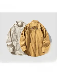 Detail of ethnic geometric embroidery on cotton work shirts in beige and mustard colors