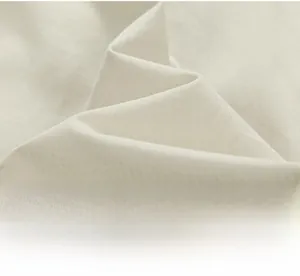 Detail shot of light beige cotton fabric with fine herringbone weave texture and soft drape