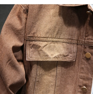 Dettaglio giacca di jeans marrone vintage con trama in cotone e cuciture della tasca