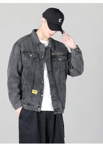 Detail of dark grey washed denim jacket featuring brand embroidery and chest pocket