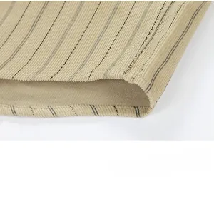 Close-up of the beige corduroy shirt hem showing detailed black vertical stripes and stitching