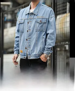 Detail view of light blue denim jacket with chest pockets and yellow woven label