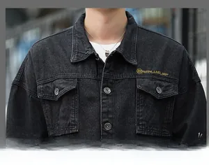 Detail of black washed denim jacket featuring yellow chest embroidery and front pockets