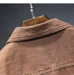 Dettaglio del colletto di una giacca di jeans marrone con cuciture rinforzate e trama twill