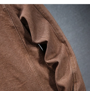 Dettaglio macro del tessuto denim marrone scuro con cuciture precise e trama saia