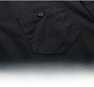 Detail of a minimalist black shirt chest pocket with a button and vertical fabric texture
