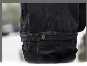 Detail view of denim jacket hem with metallic button and adjustable waist strap