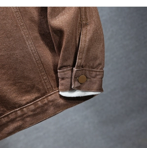 Dettaglio dei polsini della giacca di jeans marrone con fodera in maglia bianca e bottoni
