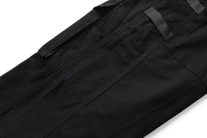 Detailansicht einer seitlichen Cargotasche mit Patte und verstärkten Nähten bei schwarzer Hose