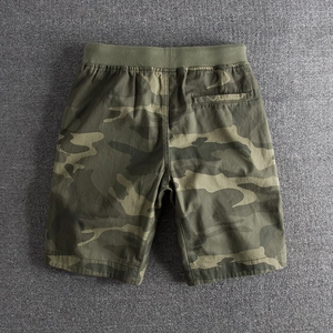 Detail of camouflage shorts featuring elastic waist and back pocket on grey texture