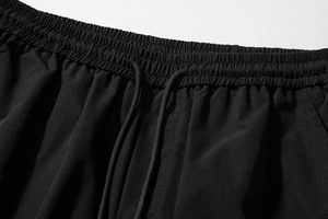 Detail showing elastic waist and drawstrings on black cargo shorts with high-quality stitching