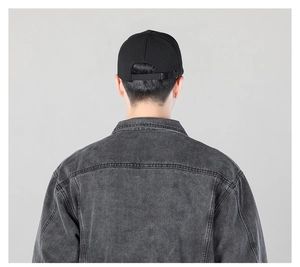 Detail view of denim jacket back texture and black adjustable cap on model back