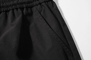 Detail of black cargo shorts featuring wide elastic waistband and reinforced side pockets