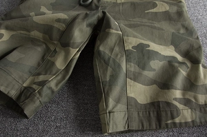 Detailed macro view of camo cargo shorts showing reinforced stitching and cotton texture