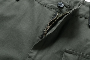 Detailansicht von Metallreißverschluss und Knopf an olivgrüner Cargo-Shorts